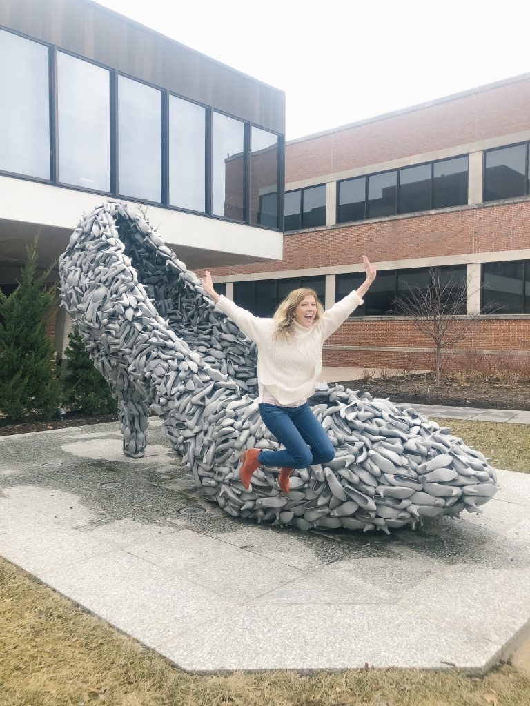 How I quit my corporate job and transitioned to self employment. Image of woman jumping in the air in front of a giant shoe.