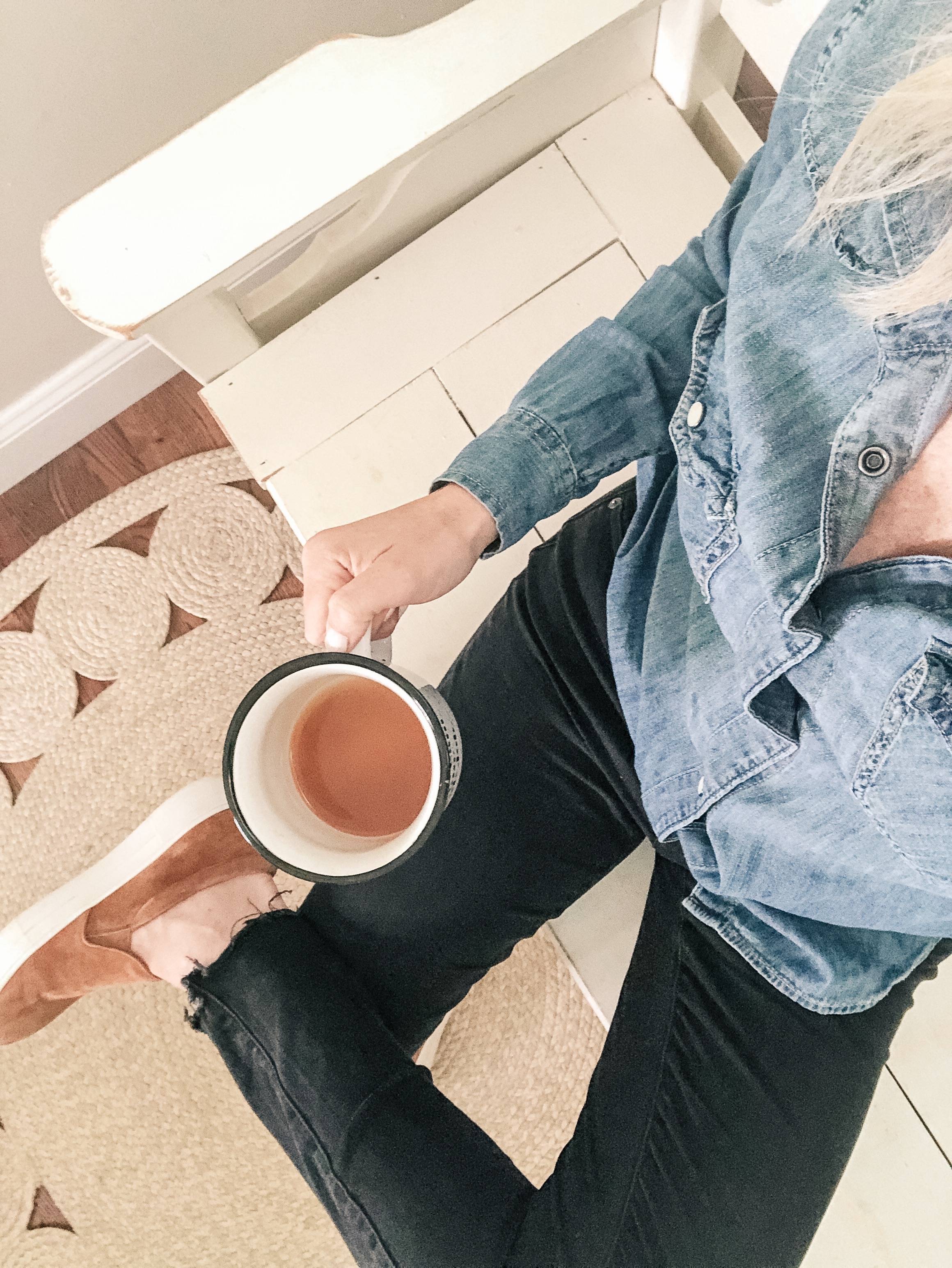girl sitting holding coffee cup wearing chambray shirt and black denim